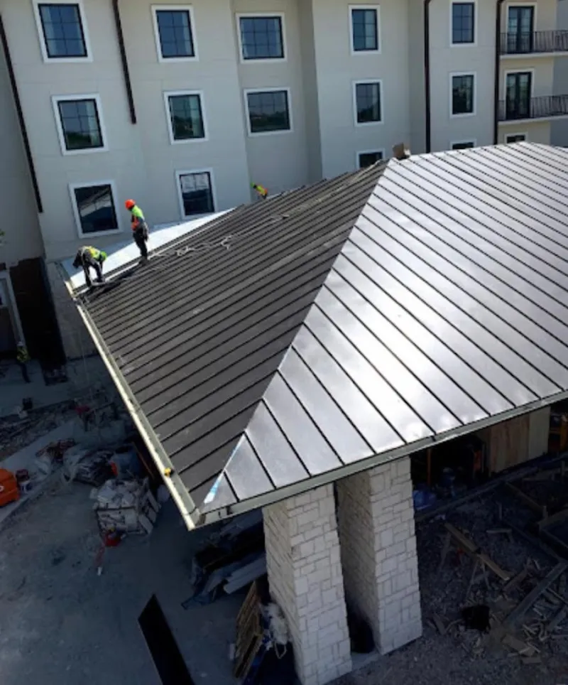 Crew installing standing seam metal roof panels on a commercial project in Travis Ranch